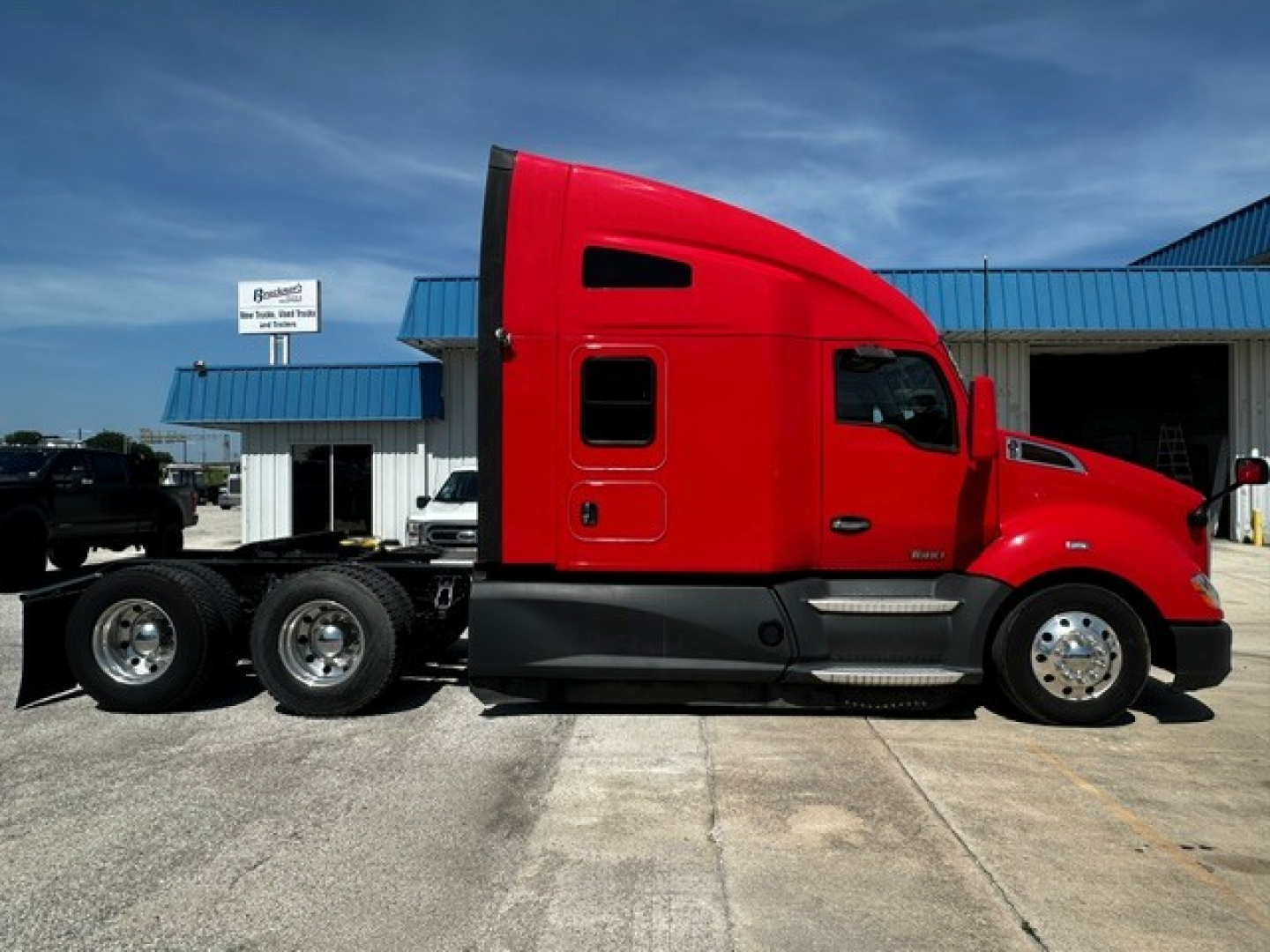 Kenworth T680 tractor in red, side view showing cab, chassis with dual rear axles, and fuel/access panels.