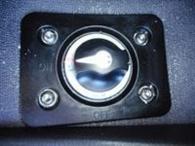 Fuel cap embedded in a blue surface with four screws around a circular lock-style cap.