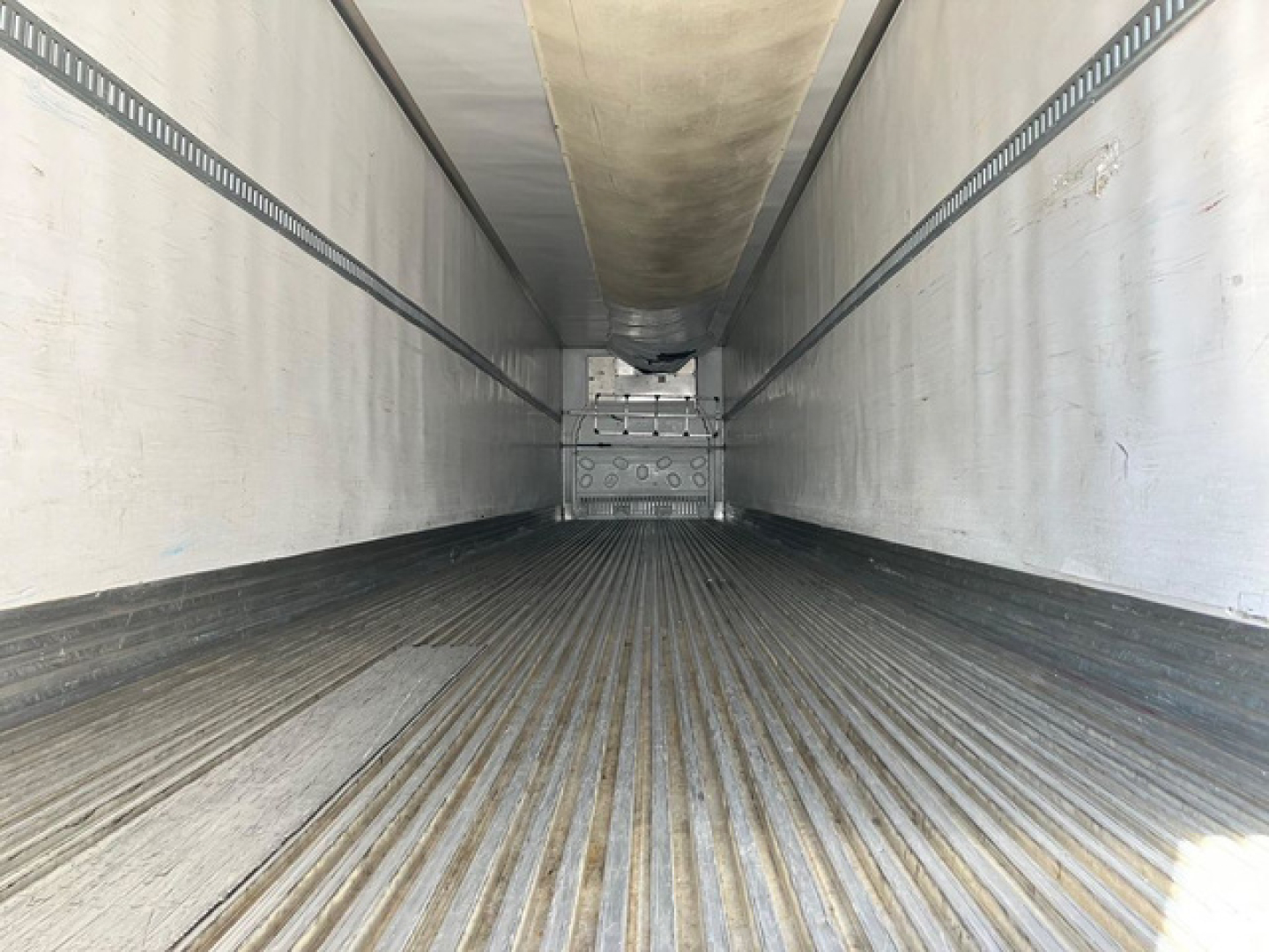 Interior of a refrigerated trailer with ribbed floor and side walls, empty cargo area. No text visible inside.