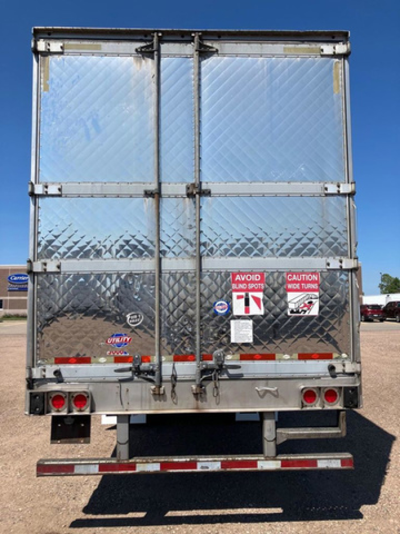 Utility reefer trailer rear showing diamond plate aluminum doors, rear bumper, taillights, and safety decals.
