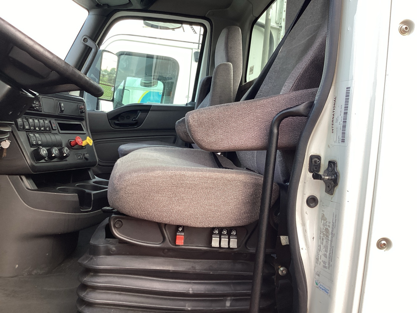 Truck cab interior of 2021 International LT625 showing driver seat and dashboard with controls and door trim.