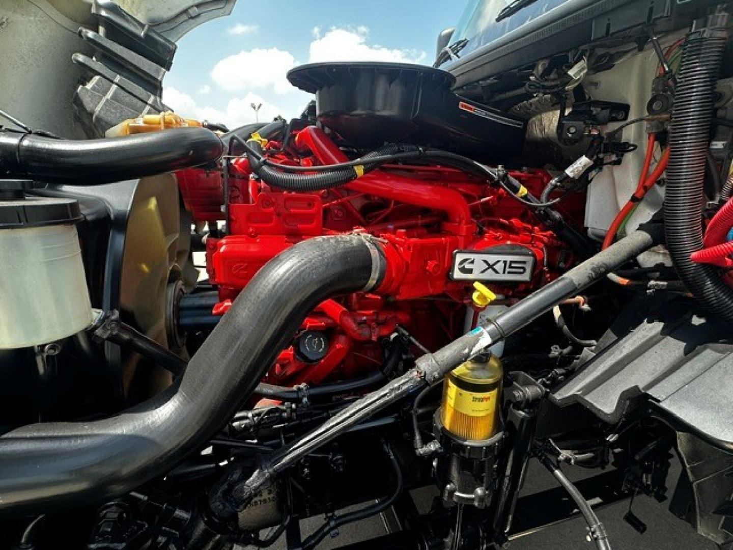 International LT625 engine bay showing red X-Series engine with intake, hoses, and yellow filter housing.