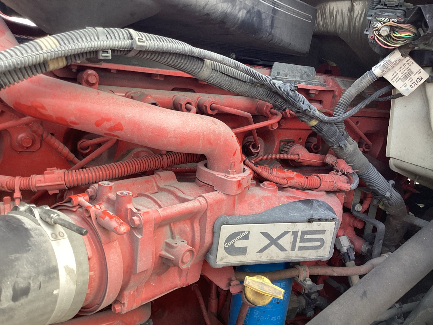 Engine bay of a 2021 International LT625 showing a red engine with Cummins X15 badge and surrounding hoses and wiring.