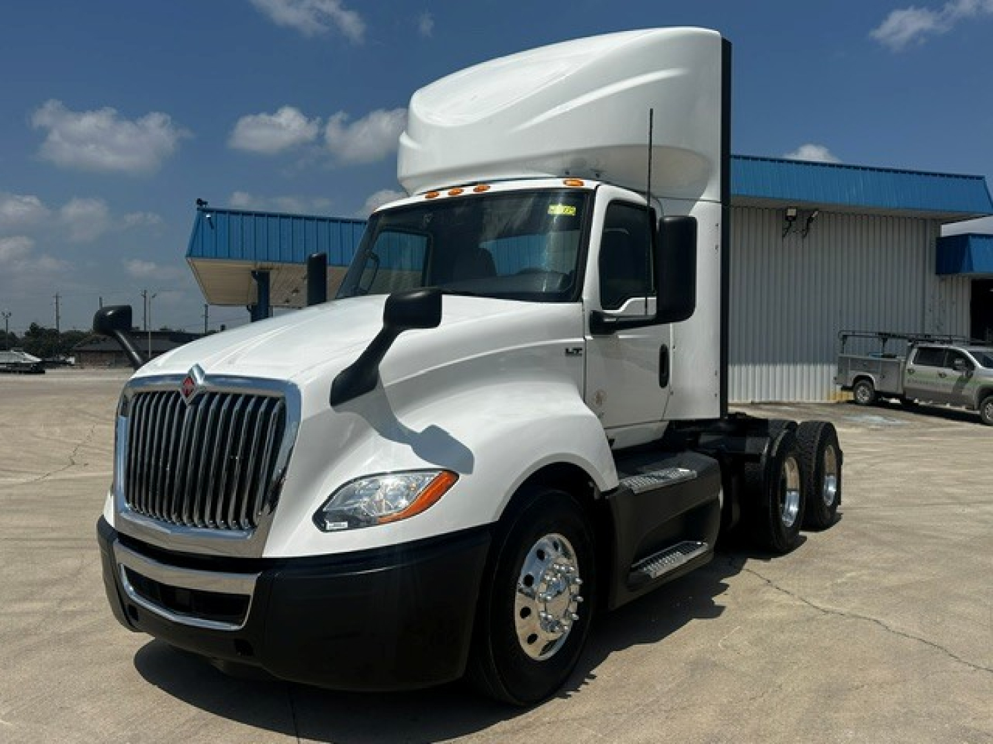 International LT625 daycab truck in a lot showing front grille, cab, and dual rear axles with sleeper.