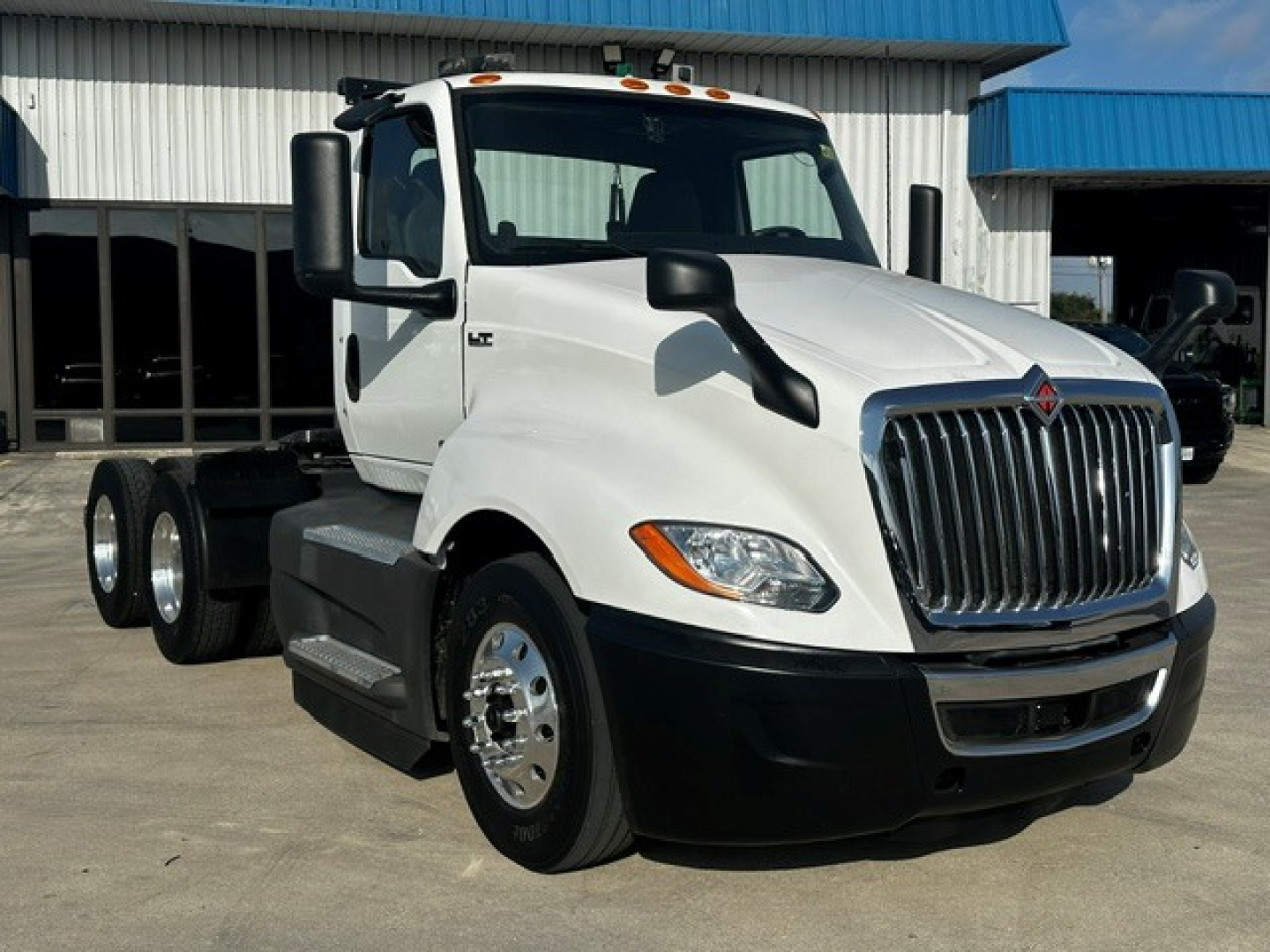 Truck cab and chassis showing International LT Series grille and dual rear axles with white cab, black bumper, and chrome mirrors.