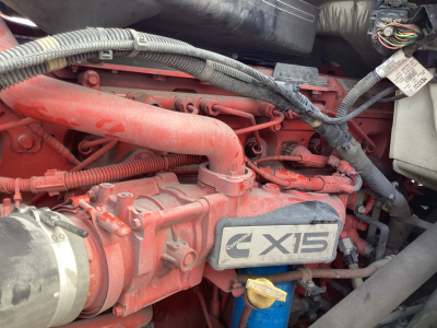 Engine bay of a 2021 International LT625 showing a red engine with Cummins X15 badge and surrounding hoses and wiring.