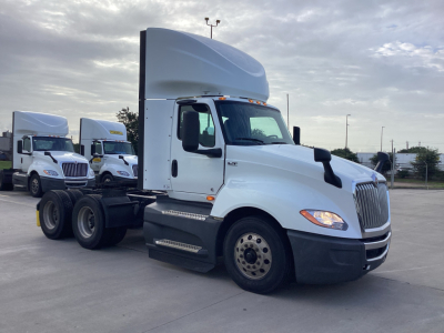 White International LT625 daycab truck in a lot with other trucks in background. Side view showing cab, fuel tanks, and dual rear axles. No visible text on the truck from this angle.
