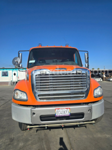 Front view of a bright orange 2015 Freightliner M2 112 sweeper truck with large chrome grille, bumper, and California license plate EC4X73.