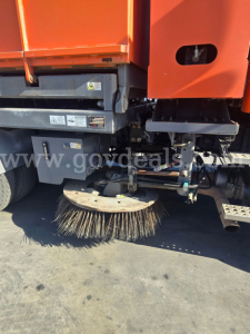 Sweeper attachment on a Freightliner M2 112 side view showing circular street sweeping brush and hydraulic supports.