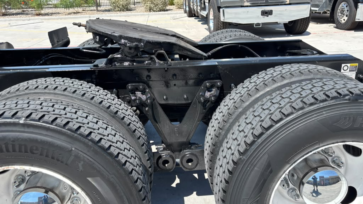 Kenworth T680 chassis rear view showing dual rear axles and frame cross-members with tires and hitch area visible.