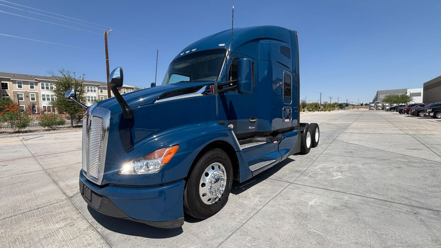 Kenworth T680 blue tractor with sleeper cab, side view showing front grille, hood, and wheels; no legible serials or stickers readable from this angle.