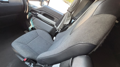 Truck cab interior showing front seat and passenger seat with fabric upholstery and seatbelt, part of Kenworth T680 cabin.