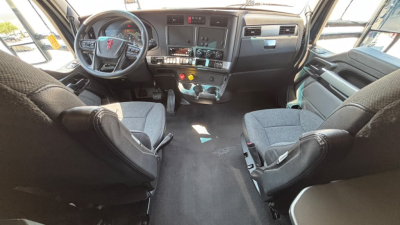Kenworth T680 interior cabin view from driver and passenger seats; dashboard with steering wheel, control panels, gear shifter, and central console.