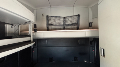 Kenworth T680 sleeper cab interior showing top bunk and storage net, side panels, and compact workspace.