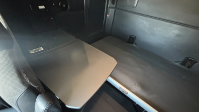 Kenworth T680 truck interior showing sleeper cab with folding table and seating area, dark panels and storage compartments visible.