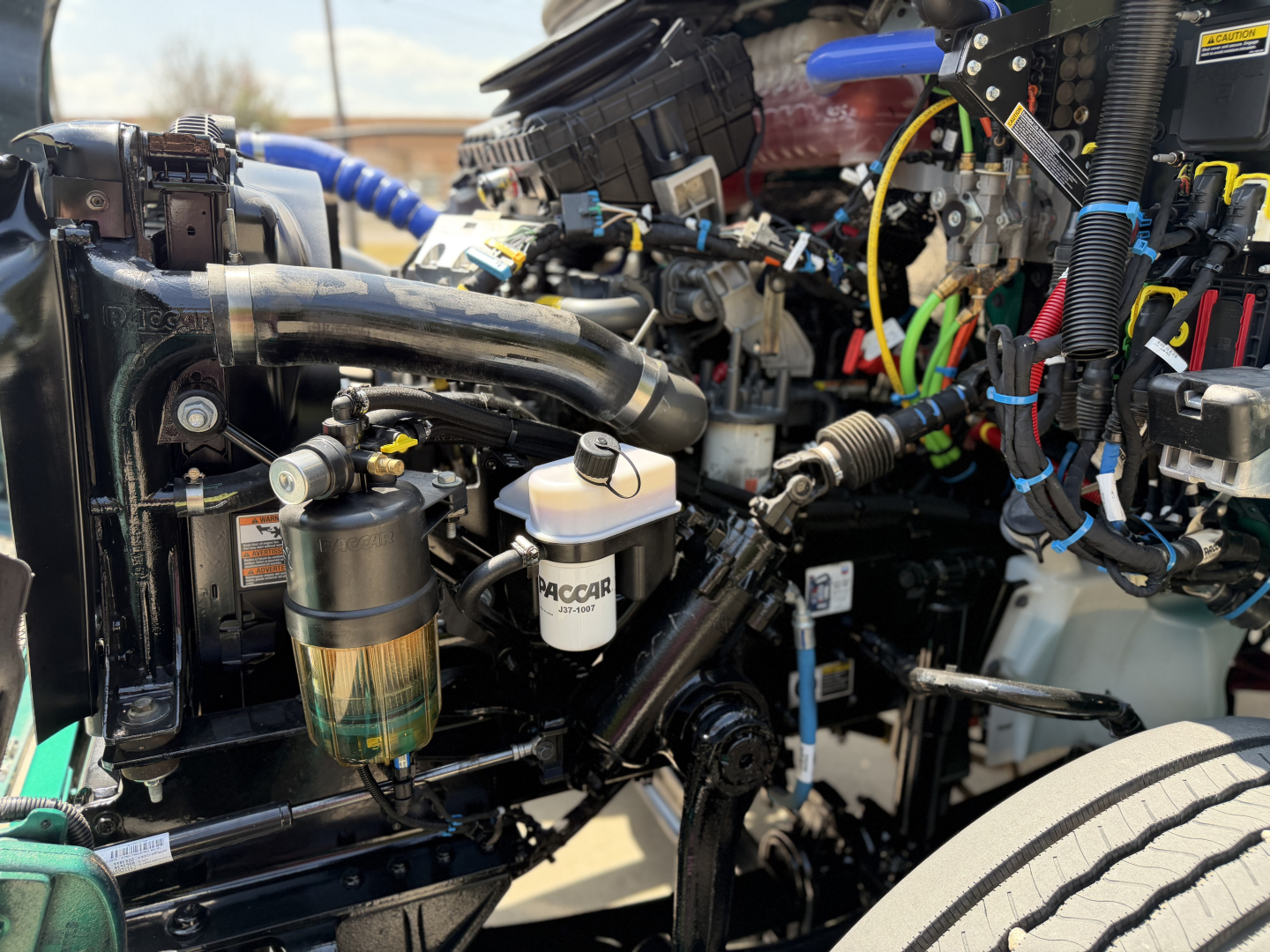 Kenworth T280 engine bay showing coolant reservoir, air filter canister, and assorted wiring harnesses.
