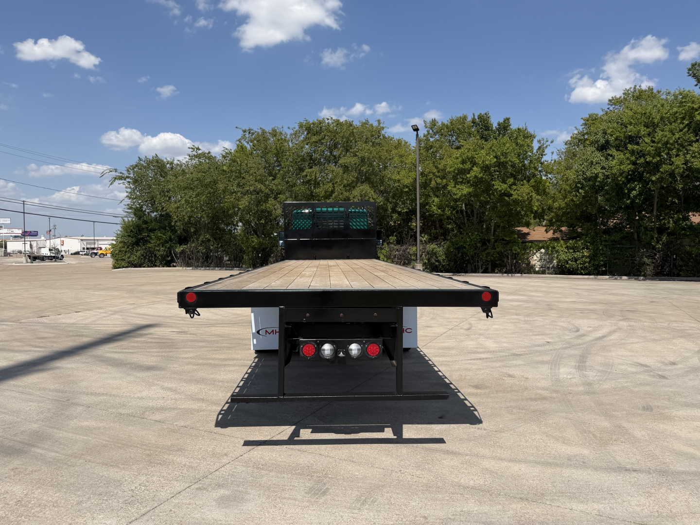 Kenworth T280 flatbed truck rear view showing flatbed and bumper with lights in an empty lot.