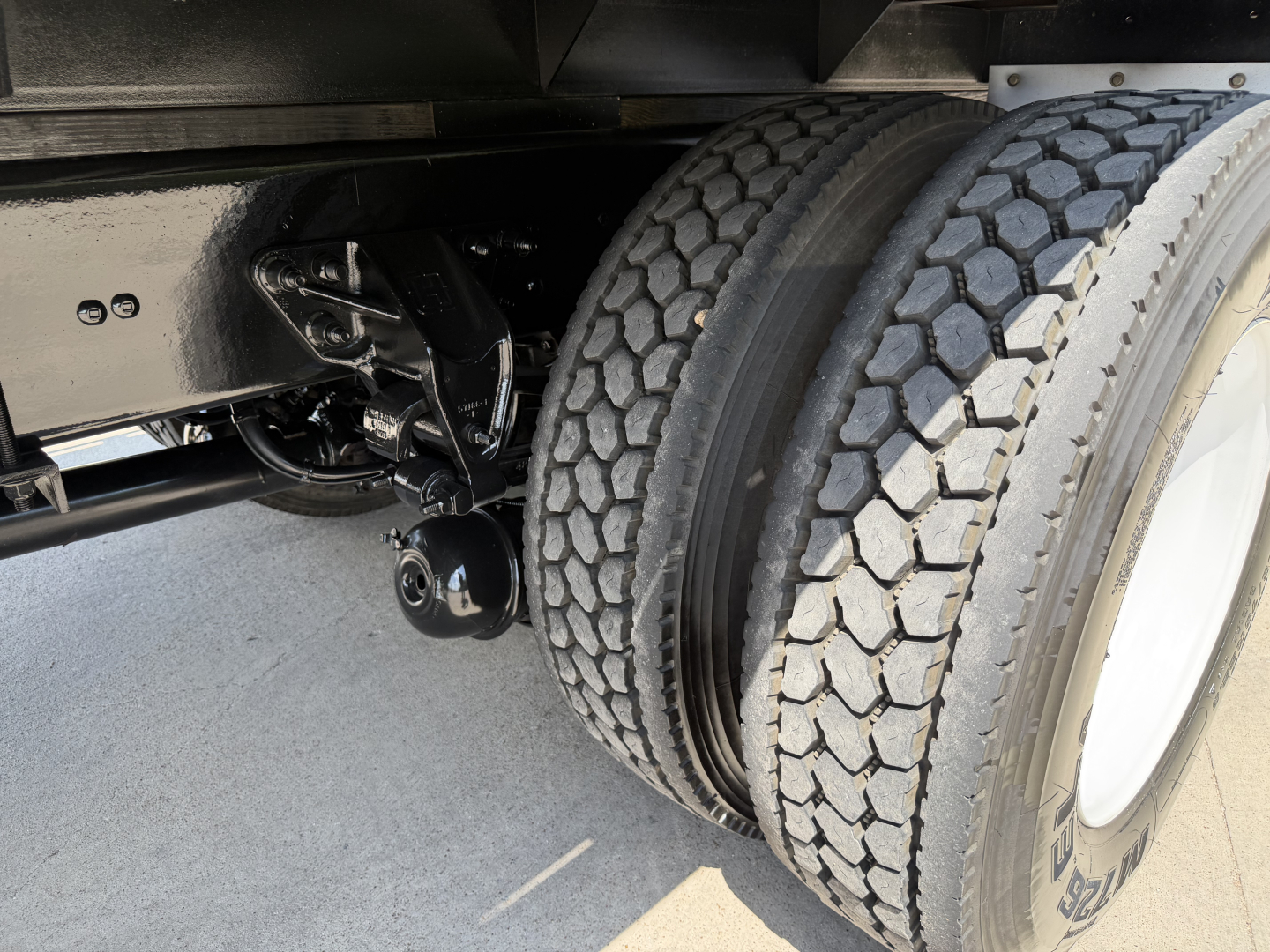 Kenworth truck rear dual tires and suspension shown in chassis area with black frame and wheel hub