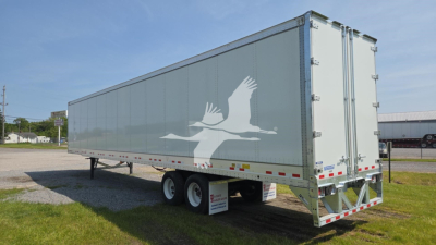 Trailer side view showing Vanguard VXP-High Base Rail with gray cargo trailer, white logo graphic of birds, dual rear doors, on dual-axle chassis.