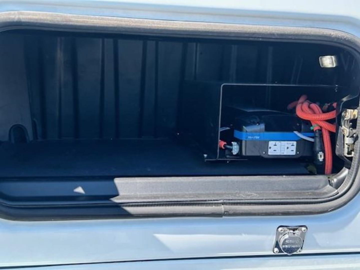 Trunk/storage area of a 2023 Freightliner Cascadia 126 sleeper showing a battery pack and wiring harness inside the luggage compartment.