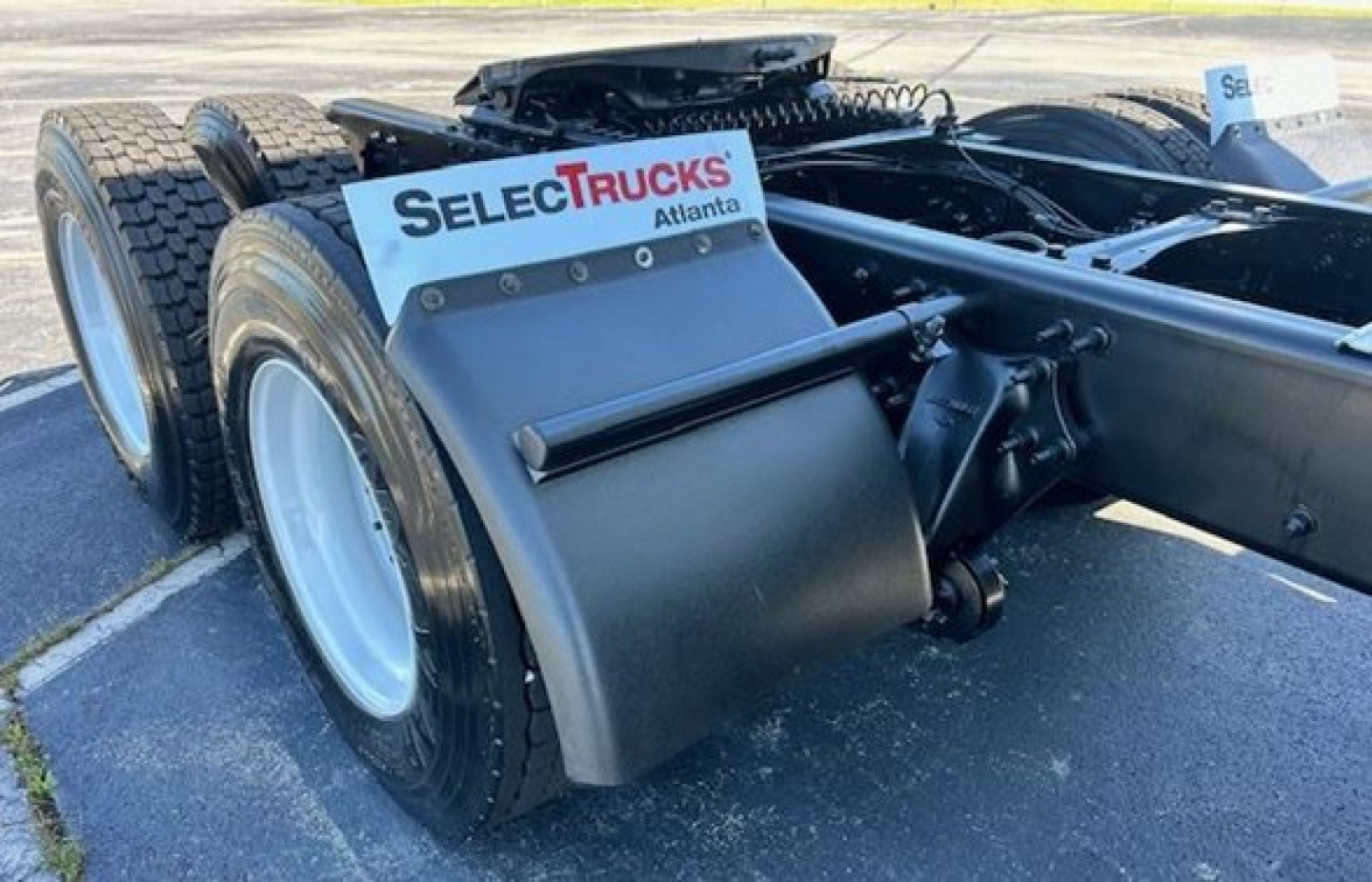 Freightliner Cascadia 126 tractor rear view showing dual rear axles, mud flaps with SelecTrucks Atlanta logo, fifth wheel mounting, and chassis components.