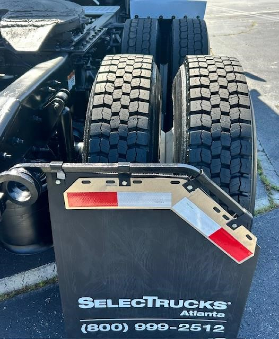 Rear view of a Freightliner Cascadia 126 tractor showing dual rear tires and bumper with reflective red/white striping. Visible are wheel assembly, chassis area, and a SelectTrucks Atlanta license plate area.