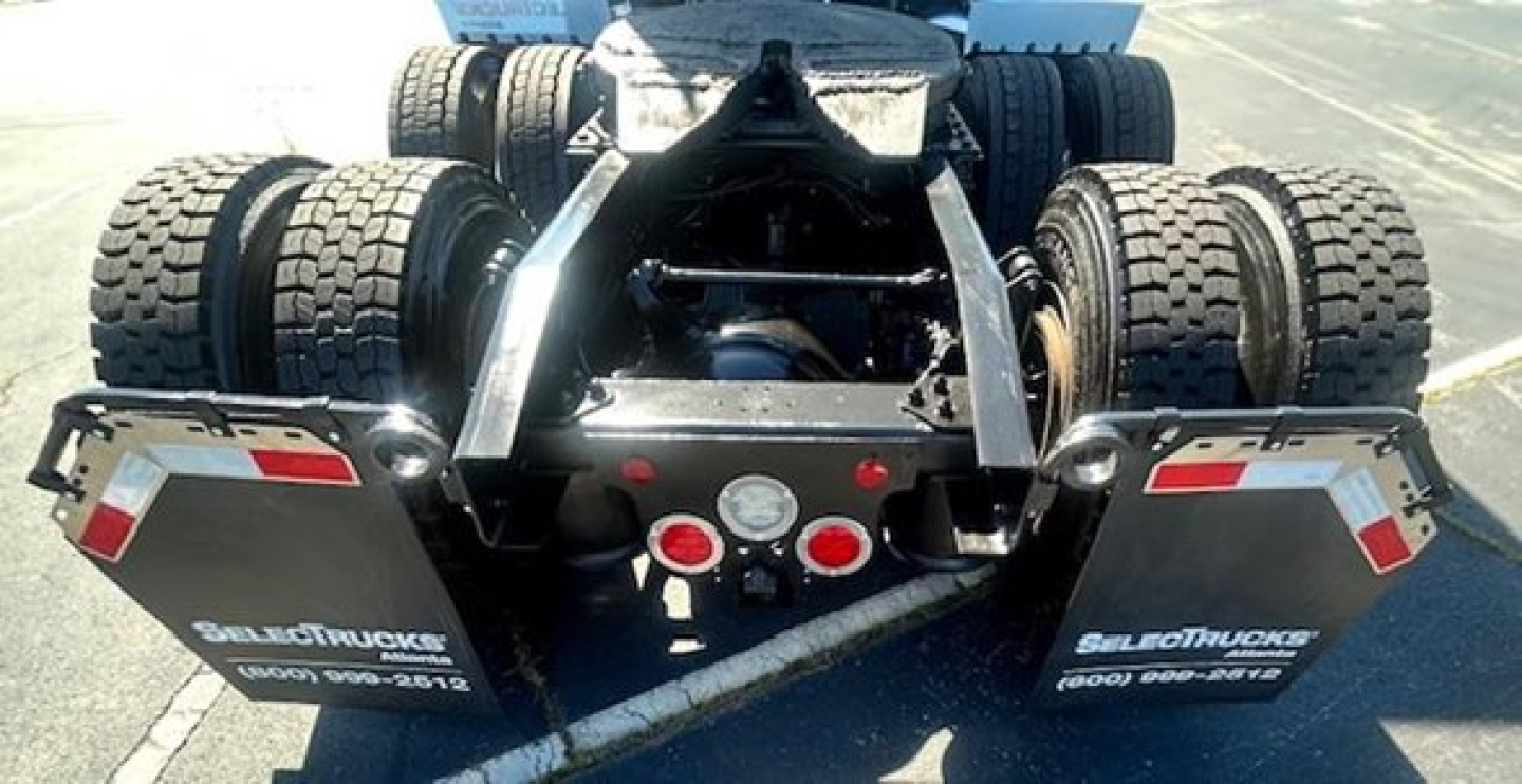 Rear view of Freightliner Cascadia tractor showing fifth wheel and dual rear tandems with mud flaps and taillights.