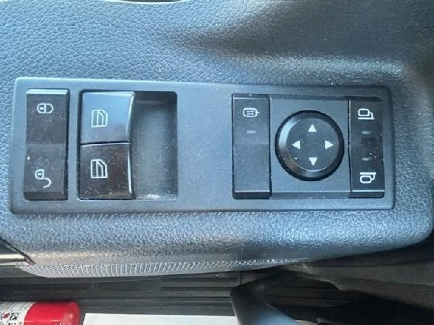 Freightliner Cascadia cab control panel with window/lock switches and joystick-style mirror control, shown from driver-side view.