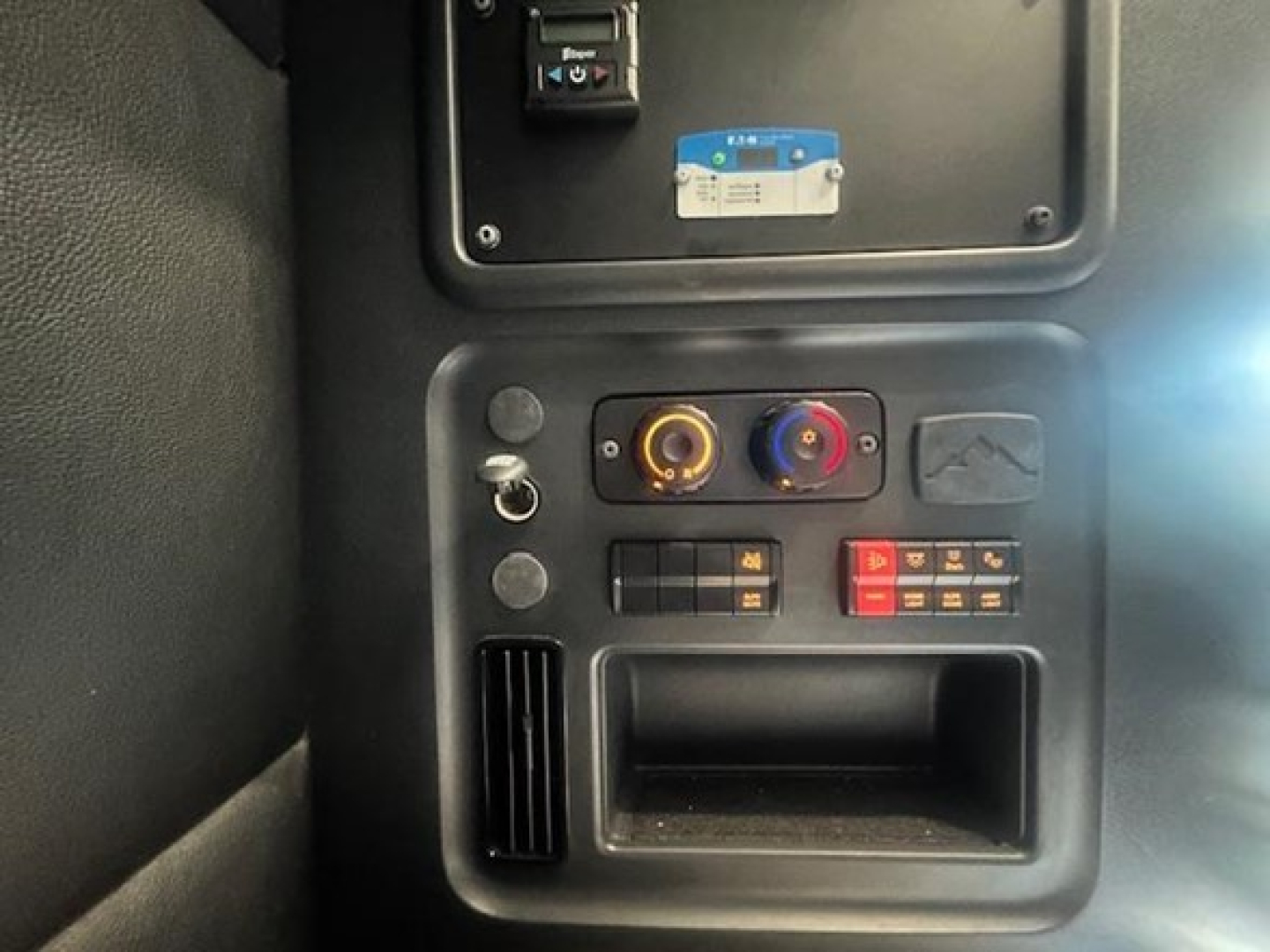 Cab interior panel of a 2023 Freightliner Cascadia showing HVAC/radio controls and storage pocket.