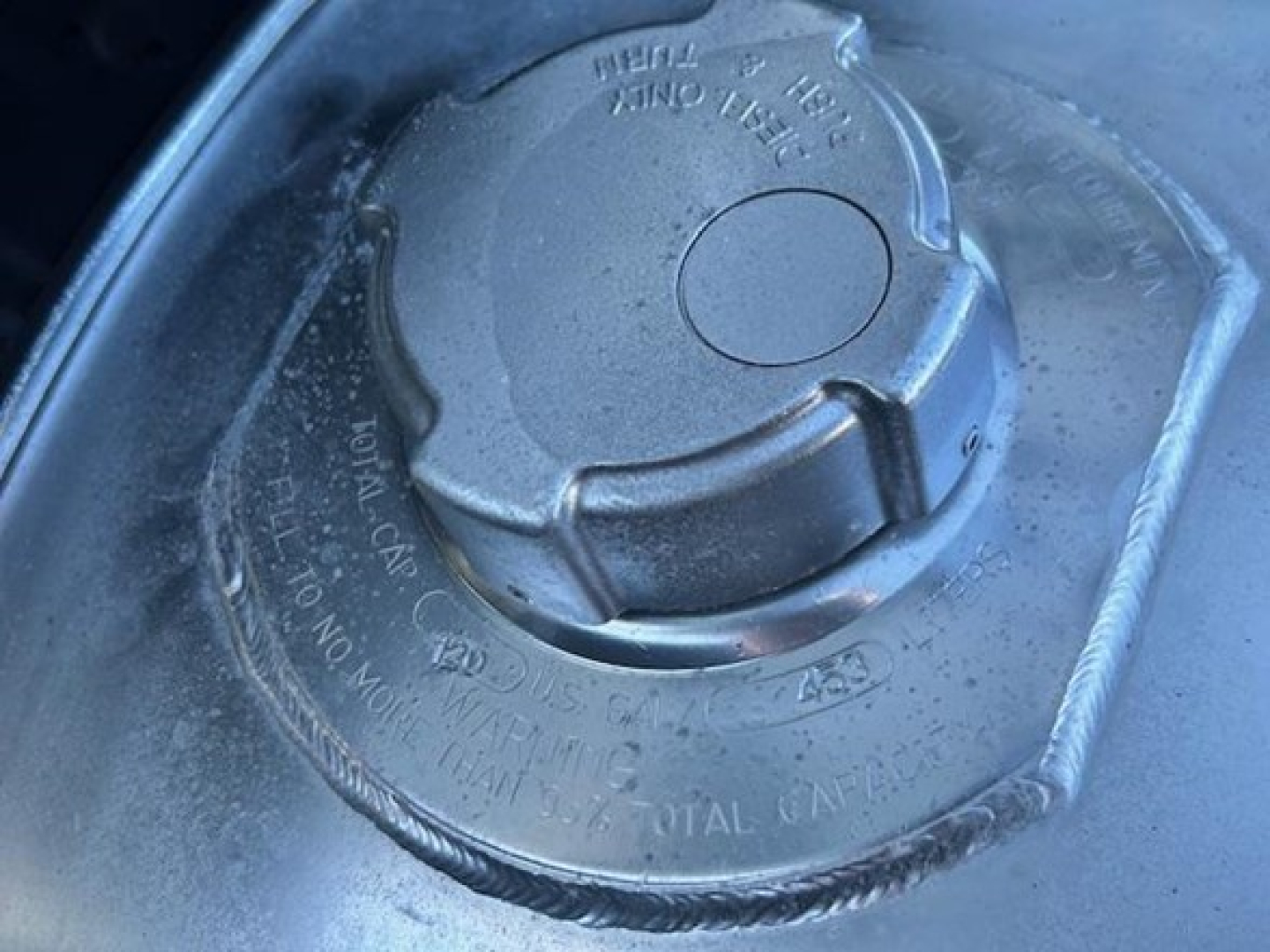 Fuel cap on Freightliner Cascadia engine bay showing locking cap and surrounding text.
