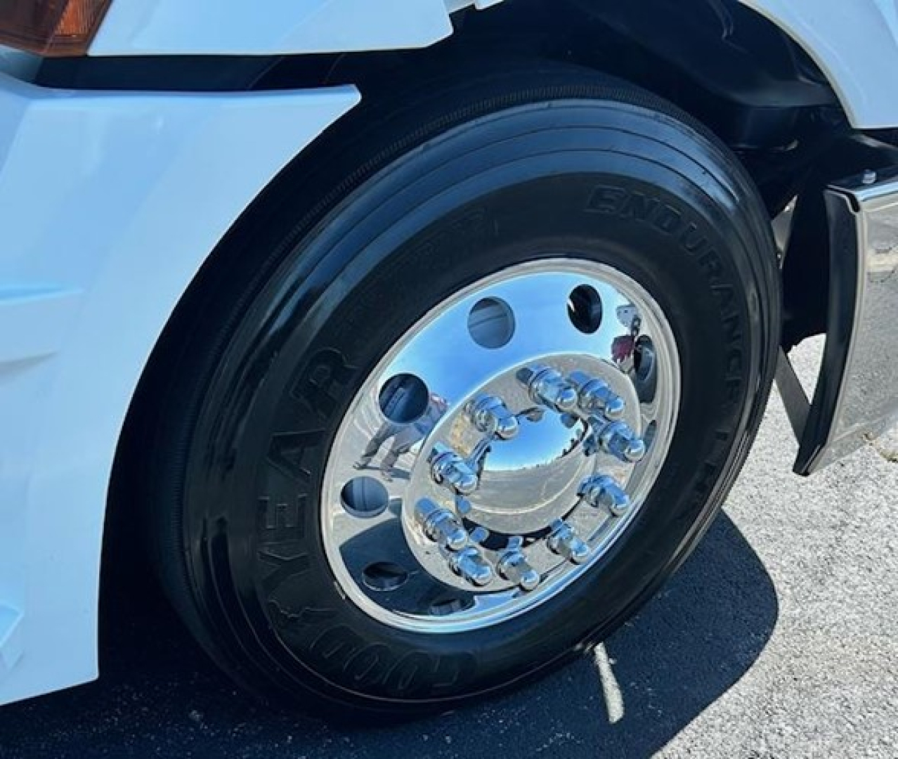 Wheel and tire of a Freightliner Cascadia truck showing Goodyear Entour tire and chrome hub with reflecting surface.