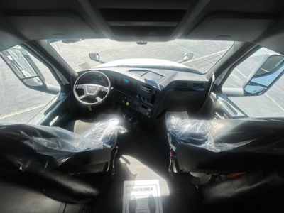 Freightliner Cascadia 126 cab interior view with steering wheel and dashboard. Driver and passenger seats wrapped in plastic.