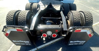 Rear view of Freightliner Cascadia tractor showing fifth wheel and dual rear tandems with mud flaps and taillights.