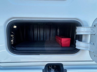 Freightliner Cascadia 126 engine bay showing storage compartment with small red toolbox