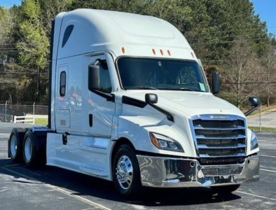 Truck cab showing 2023 Freightliner Cascadia 126 in white with chrome front bumper and grille, sleeper cab, side mirrors, and dual rear axles.