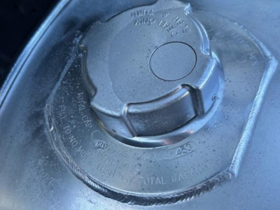 Fuel cap on Freightliner Cascadia engine bay showing locking cap and surrounding text.