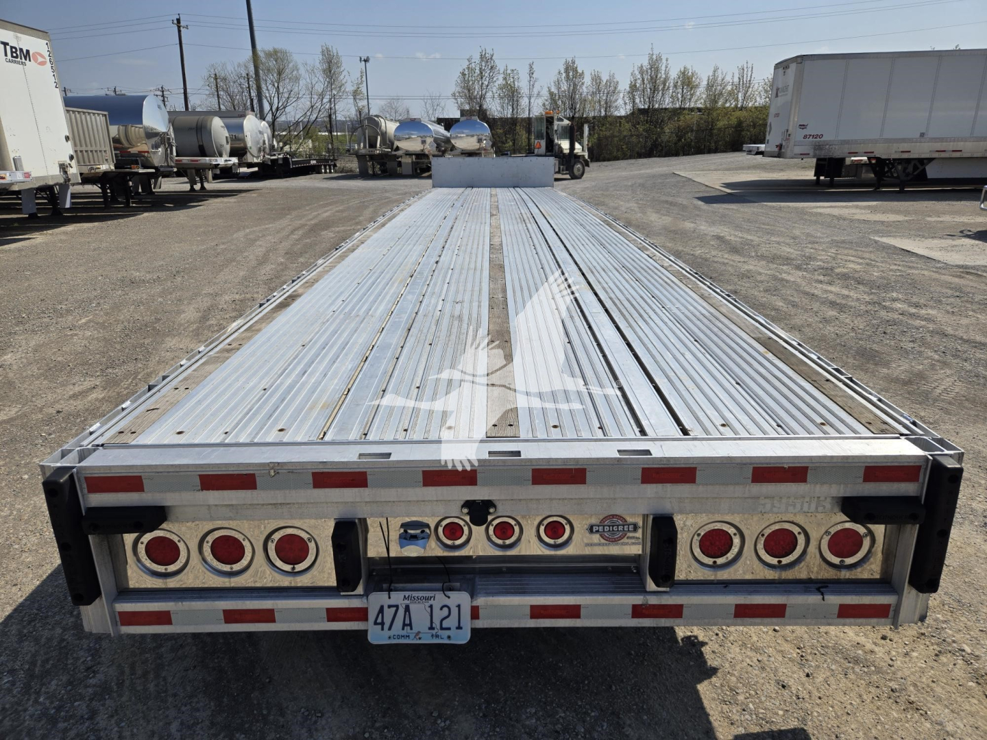 Trailer rear showing drop deck flatbed with multiple LED taillights and reflective tape; license plate 47A 121; RBM branding and lighting fixtures visible.