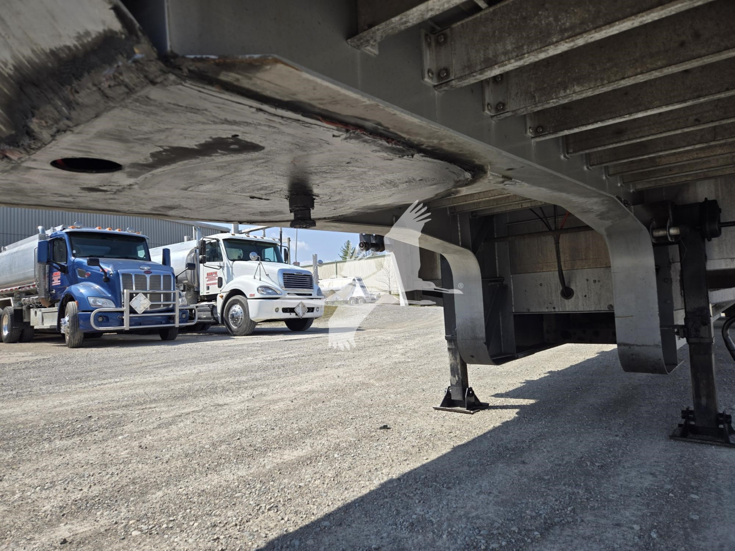 Underbelly of a 2019 Reitnouer Dropmiser trailer showing support legs and deck structure with other trucks in background.