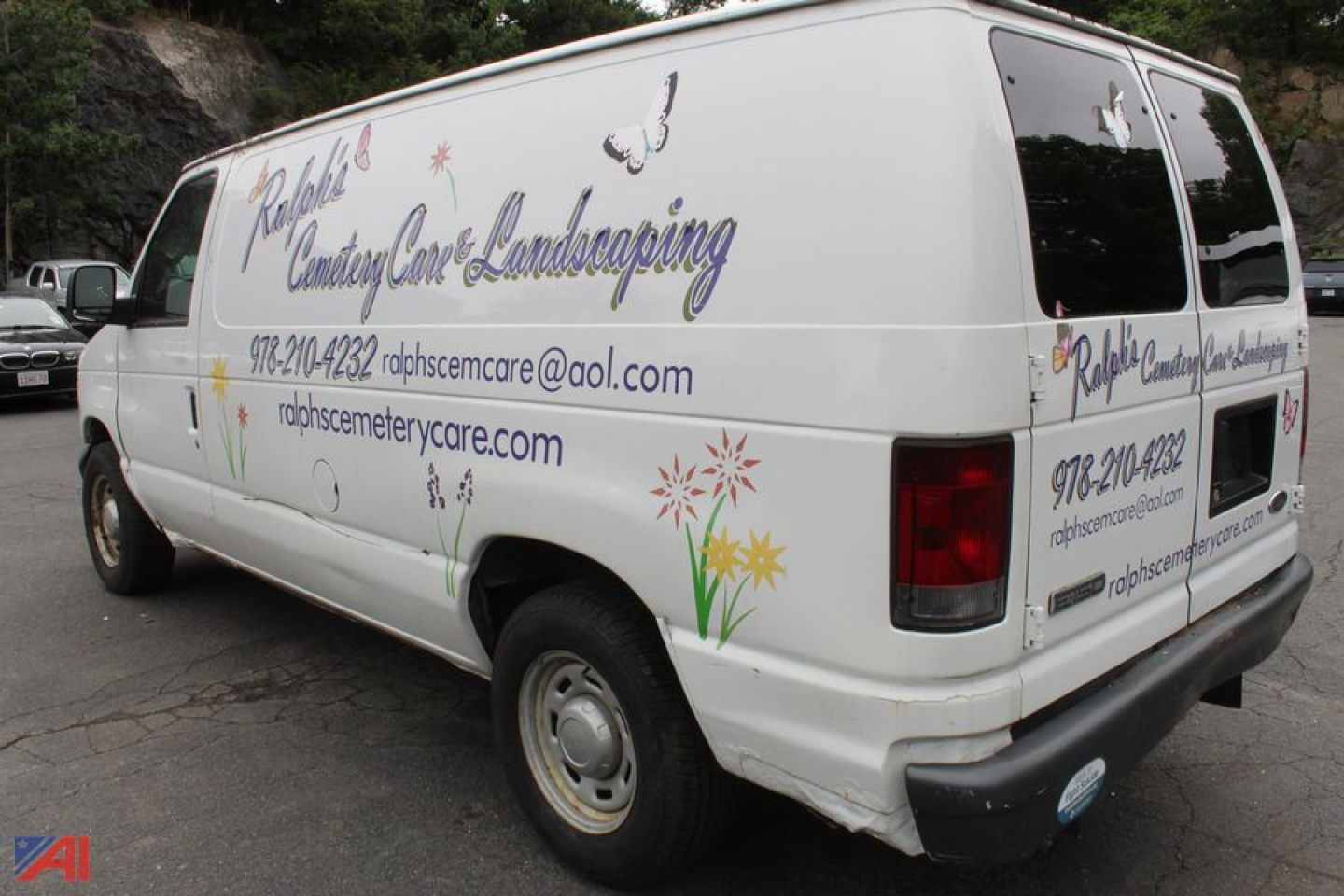 Ford E-150 cargo van with floral graphics and contact info on side and rear panels.