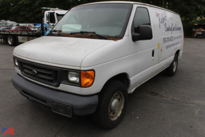 Ford E-150 cargo van in a used condition with white exterior, front grille, headlights, and side graphics visible.