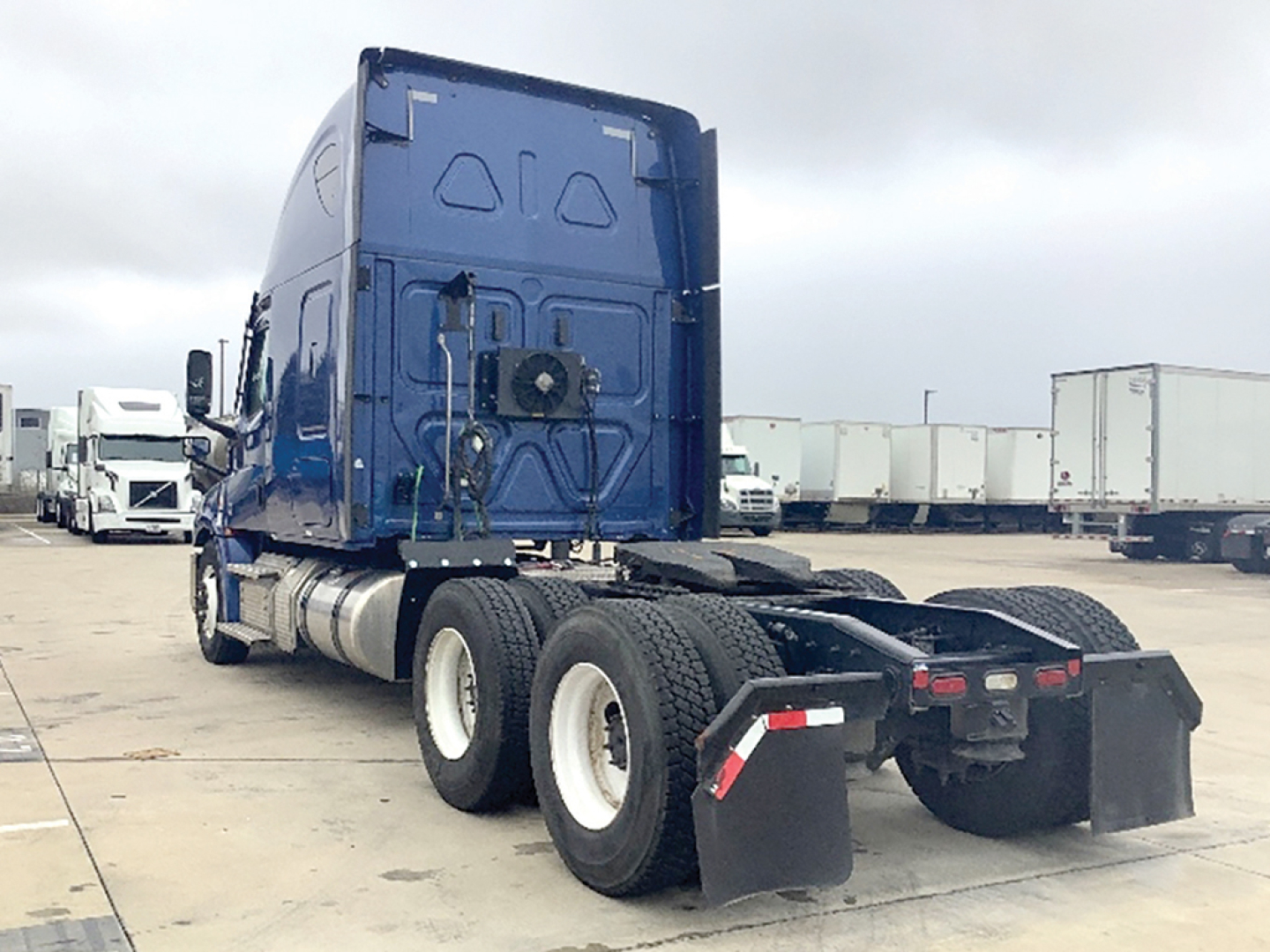 Freightliner Cascadia 126 rear view showing sleeper cab and dual rear axles with mud flaps and chassis in blue exterior.