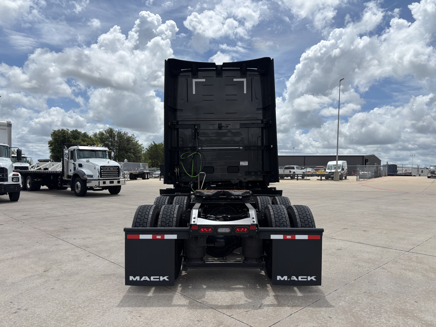 Rear view of a new 2027 Mack PR64T76H tractor showing dual rear wheels, black fifth wheel area, mud flaps with MACK branding, and stock/VIN details not visible.