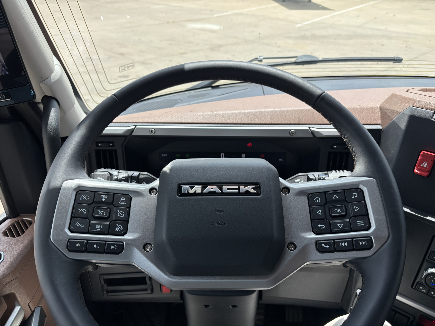 Mack PR64T76H truck interior steering wheel with control panels on both sides and dashboard visible.