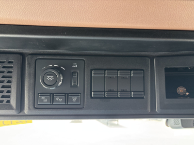 Dashboard controls of a Mack truck showing a circular dial, four rectangular switches, and a series of blank rocker panels.