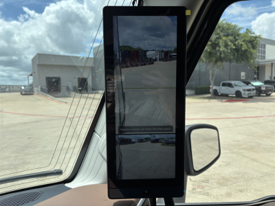 Vertical foldout display inside a truck cab showing multiple camera views and reflections of the lot outside.
