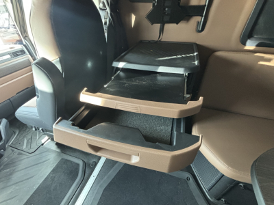 Truck interior cab drawer set extended showing brown trim and storage compartments in the Mack PR64T76H cab.