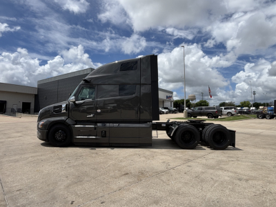 Side view of a black Mack PR64T76H conventional sleeper truck with a raised cab, dual rear axles, and no trailer attached.