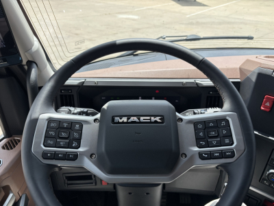 Mack PR64T76H truck interior steering wheel with control panels on both sides and dashboard visible.