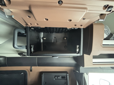 Engine bay/driver cab area of a new Mack PR64T76H showing interior storage compartment with open bottom drawer and surrounding panels.