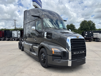 Mack PR64T76H conventional sleeper truck in dark gray, front three-quarter view, showing large grille, hood vents, and dual rear axles.